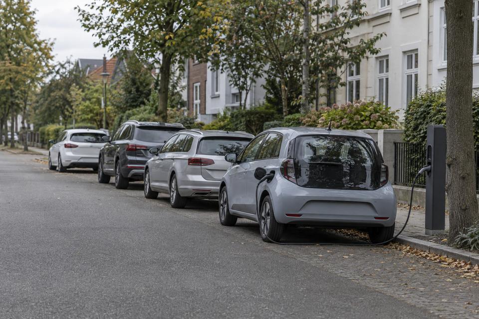 Parkerede biler på en boligvej med en elbil tilsluttet en lader